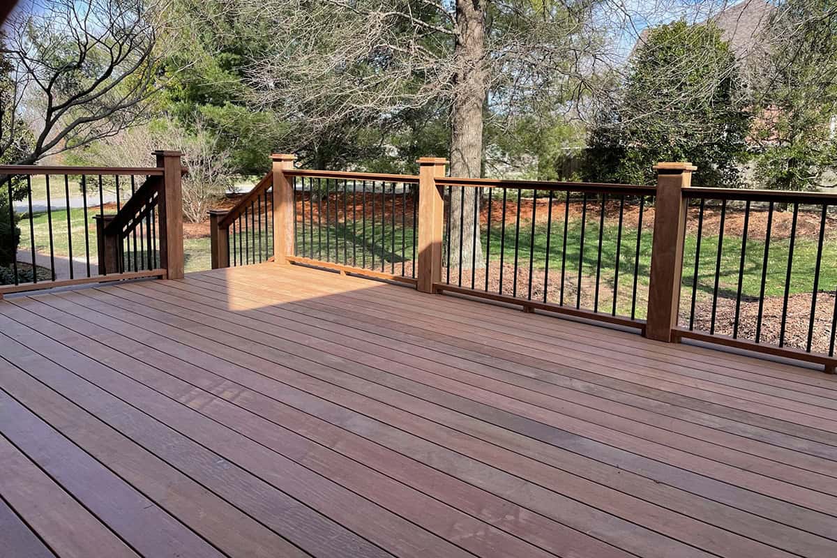 Custom wooden deck with black railing, surrounded by greenery in West Meade, TN, showcasing outdoor living space designed for beauty and durability.
