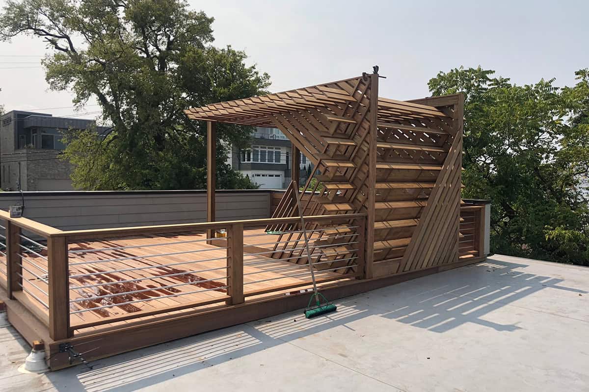Custom wooden pergola on a rooftop deck in West Meade, featuring modern design elements, providing shade and structure, surrounded by greenery.