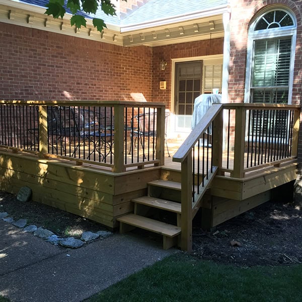 Custom wooden deck with black railing and stairs leading to a brick home, enhancing outdoor living space in Nashville, TN.