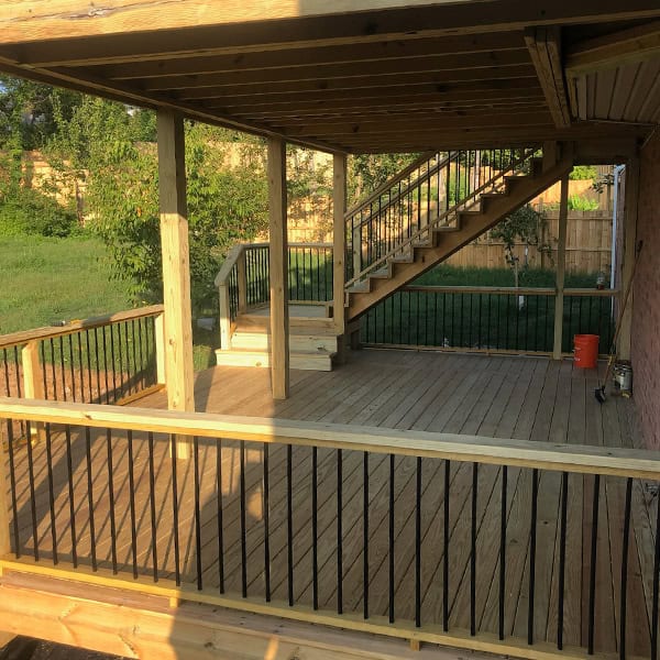 Custom wooden deck with black railings and stairs, showcasing quality craftsmanship in an outdoor space, designed for enhancing living areas in Nashville, TN.