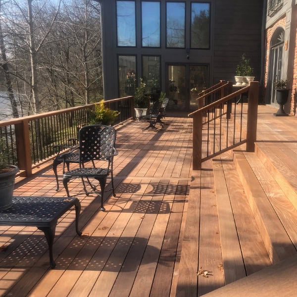 Custom wooden deck with black metal furniture, planters, and a view of trees, enhancing outdoor living space for Nashville homeowners.