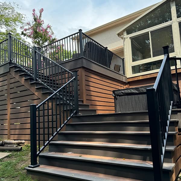 Custom wooden deck with black railing and stairs leading to a home, showcasing outdoor living space enhancements in Nashville, TN.