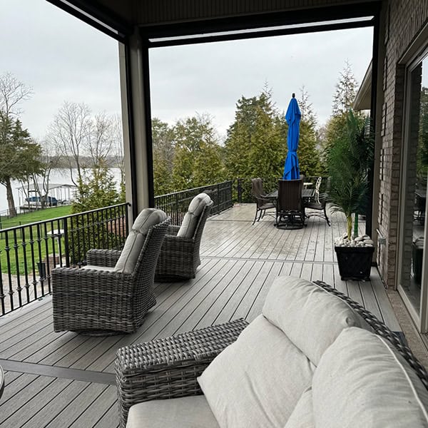 Custom deck with comfortable seating, blue umbrella, and scenic view of greenery and water, showcasing outdoor living space designed by DW Construction in Nashville, TN.