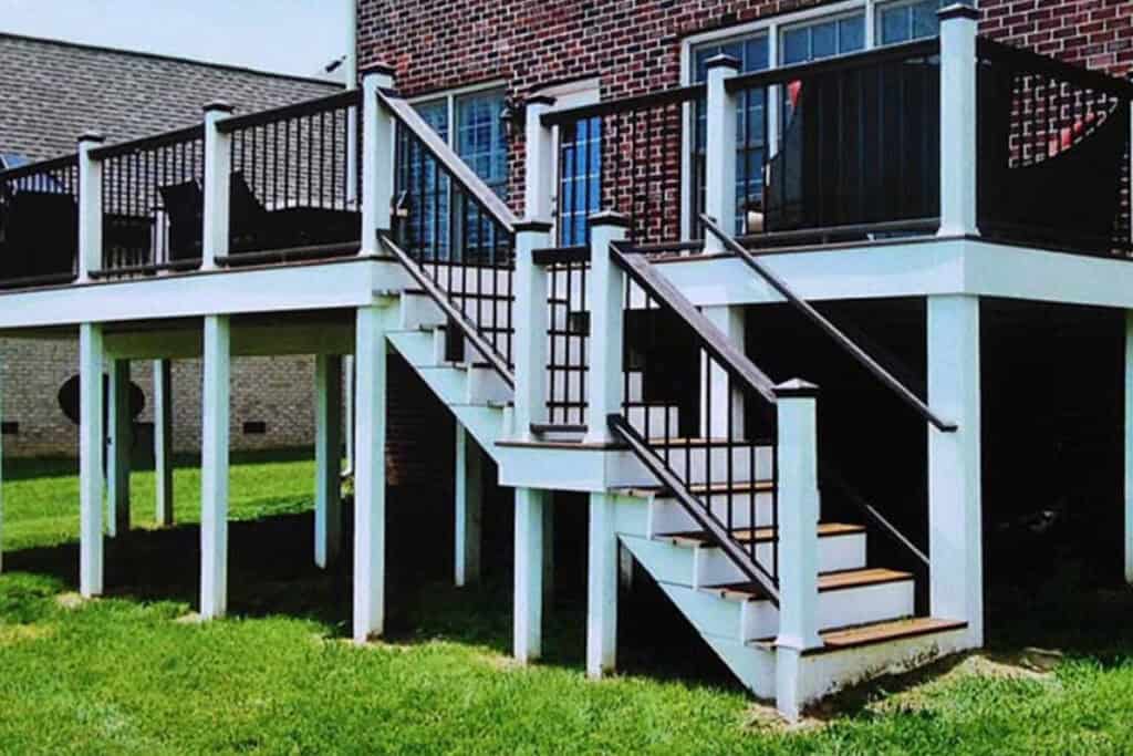 Stunning elevated deck design with black railings and white posts, showcasing steps leading down to a green lawn, ideal for Nashville outdoor living inspiration.