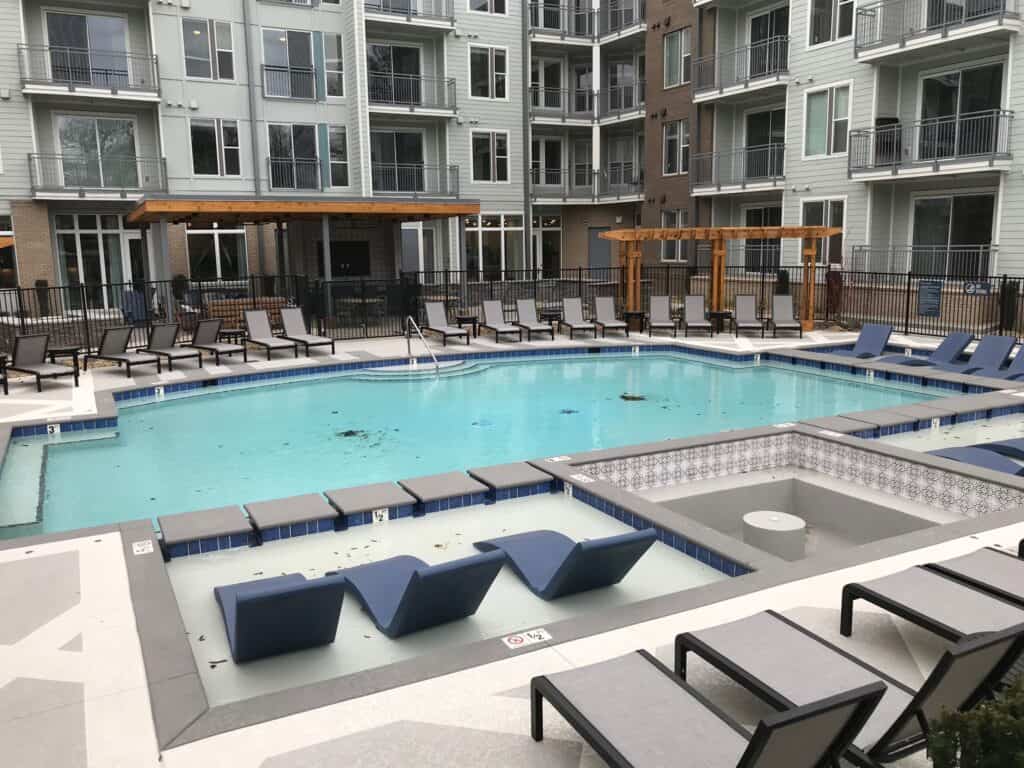 Spacious pool area with modern lounge chairs, surrounded by elegant architecture and a wooden pergola, designed for outdoor living and relaxation in Brentwood, TN.
