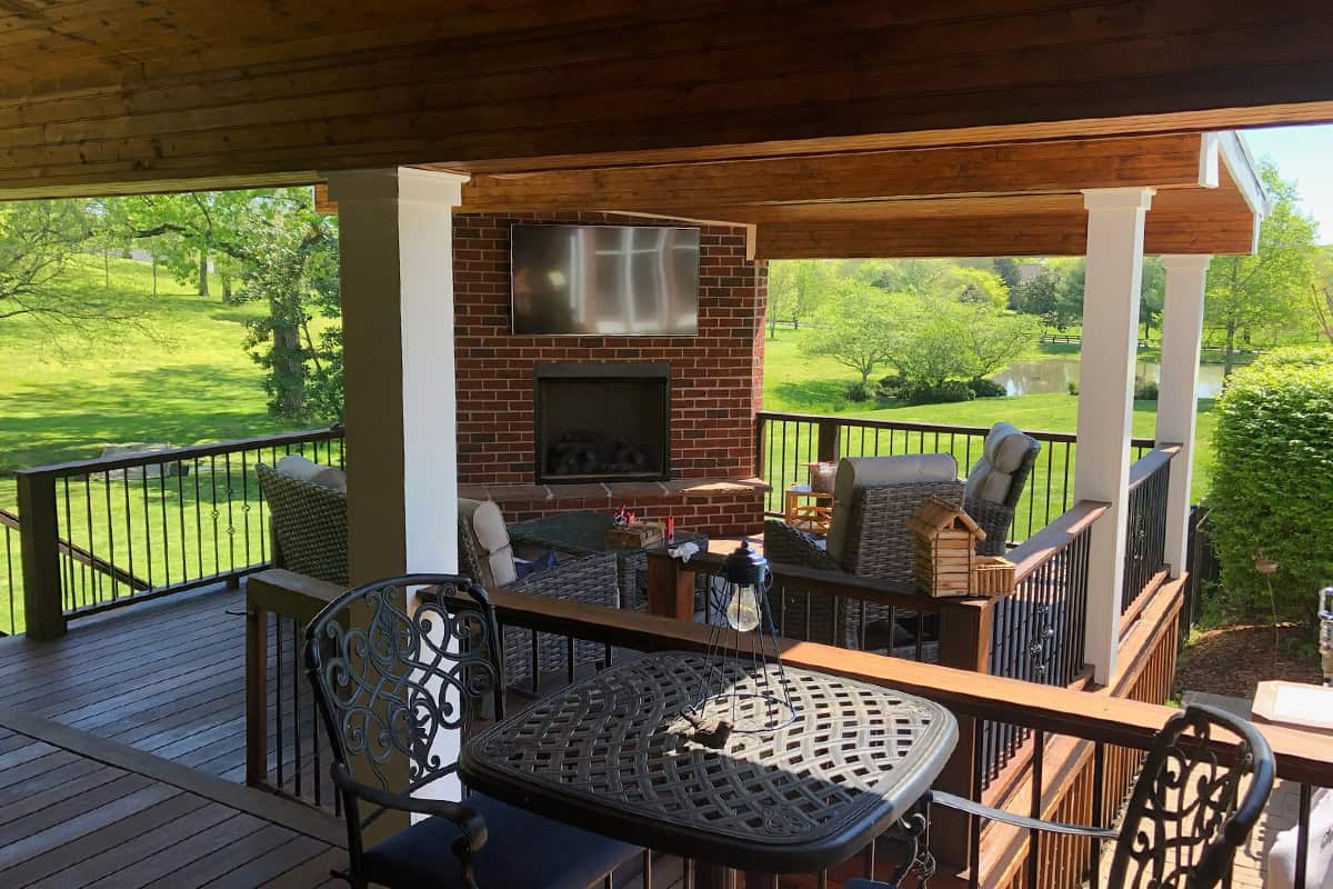 custom outdoor fire features 4 Custom outdoor fireplace with seating area on a deck, overlooking a green lawn and trees, enhancing outdoor living space in Nashville.