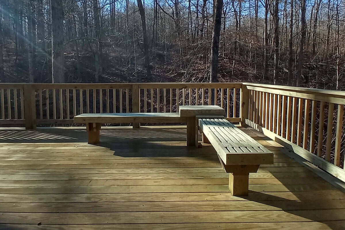 custom outdoor fire features 7 Wooden deck featuring built-in seating, surrounded by a forested area, designed for outdoor fire features and gatherings.