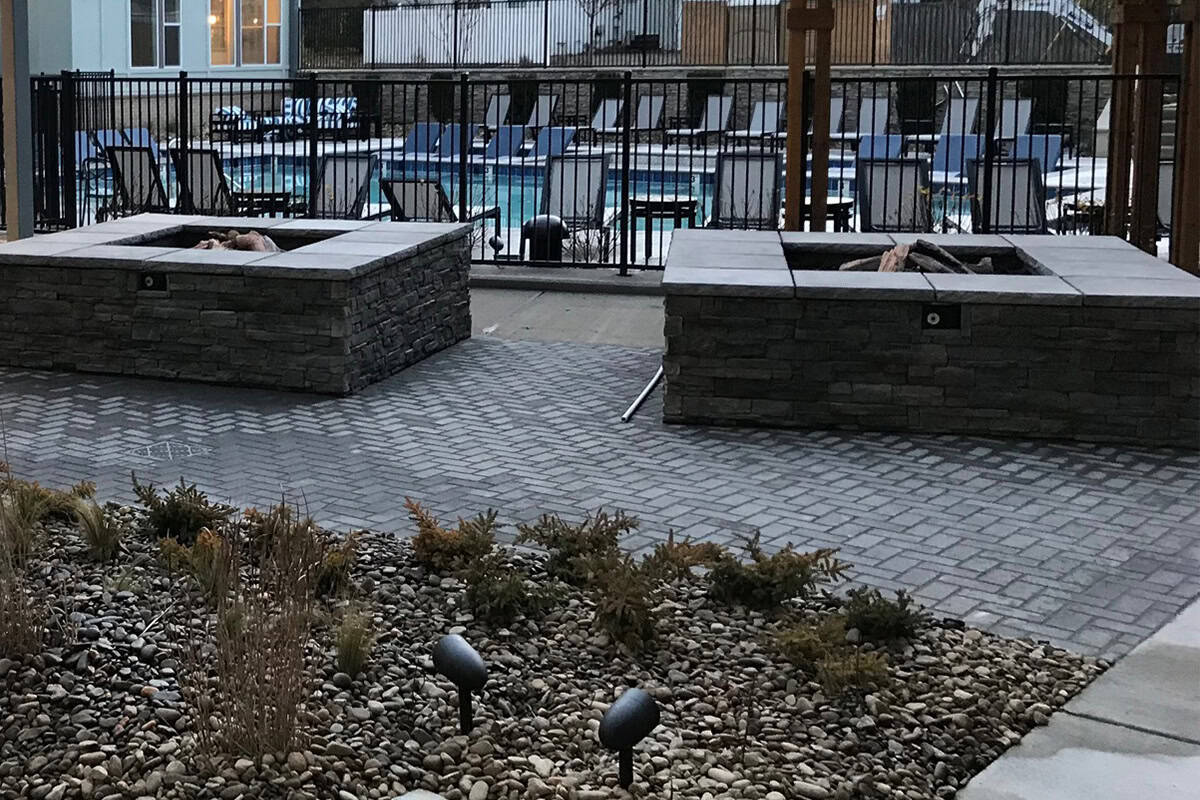 Custom stone fire pits surrounded by paver patio, featuring landscaping with decorative stones and plants, enhancing outdoor living space for relaxation and gatherings.