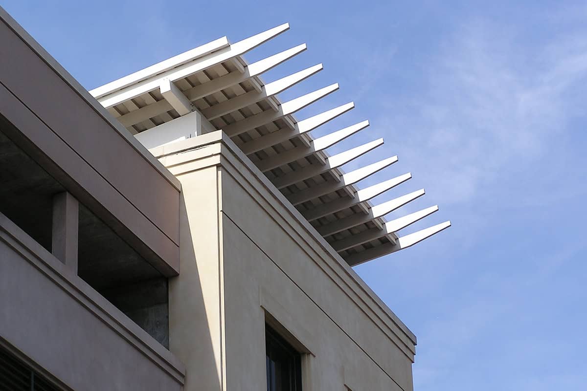 Modern aluminum pergola structure atop a building, showcasing sleek design and clean lines against a blue sky, emphasizing low-maintenance outdoor living solutions.