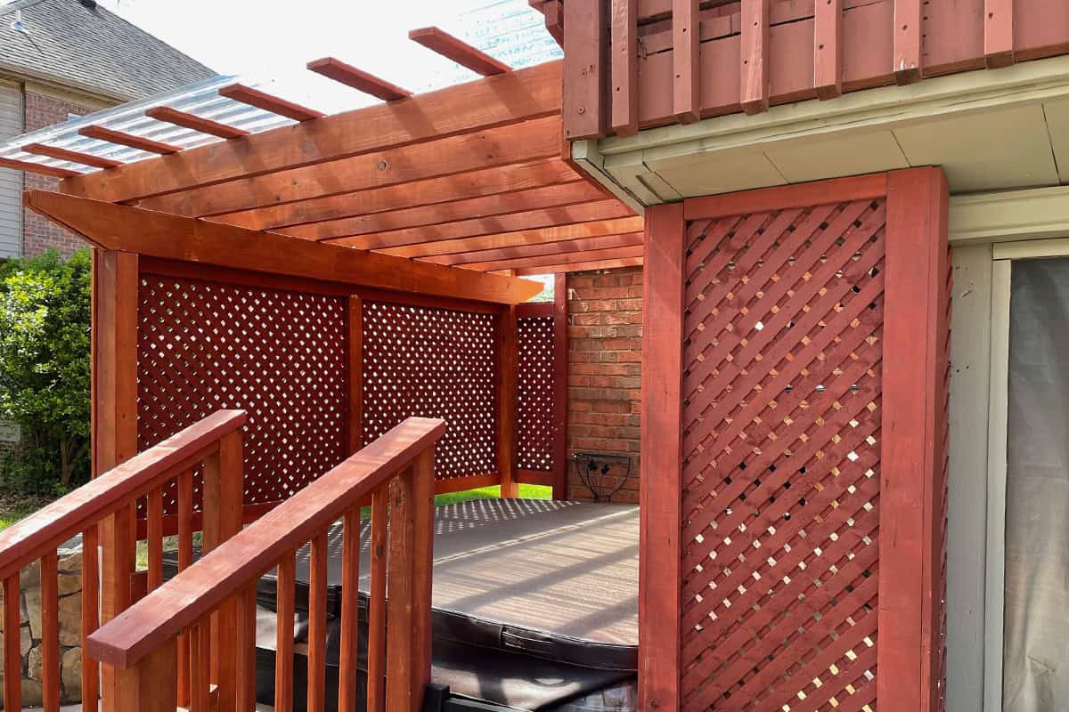 Custom wooden pergola attached to a home, featuring lattice panels and a shaded area over a hot tub, enhancing outdoor living space in Nashville, TN.