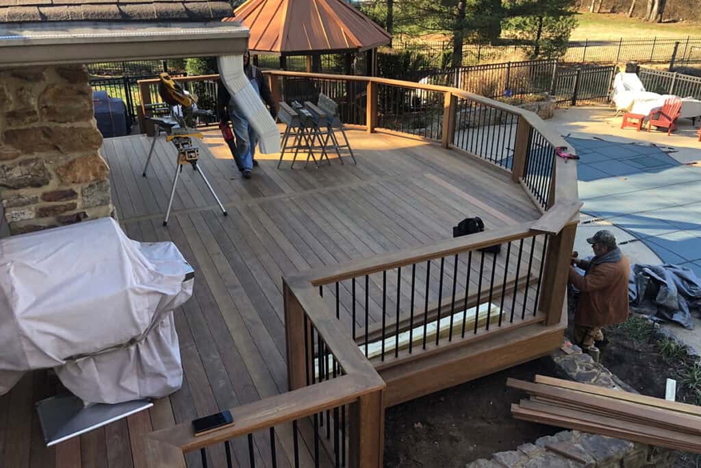 Deck construction in a Nashville backyard, featuring wooden decking, railing, and construction tools, with workers engaged in the building process.