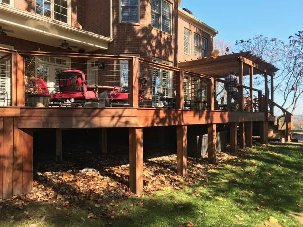 Custom wooden deck with red chairs and a pergola, showcasing outdoor living space designed by DW Construction in Nashville.