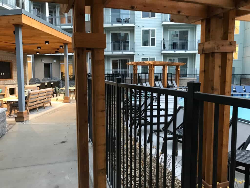 Outdoor living space featuring a wooden pergola, seating areas with benches, and a poolside view, highlighting DW Construction's design capabilities in Nashville.