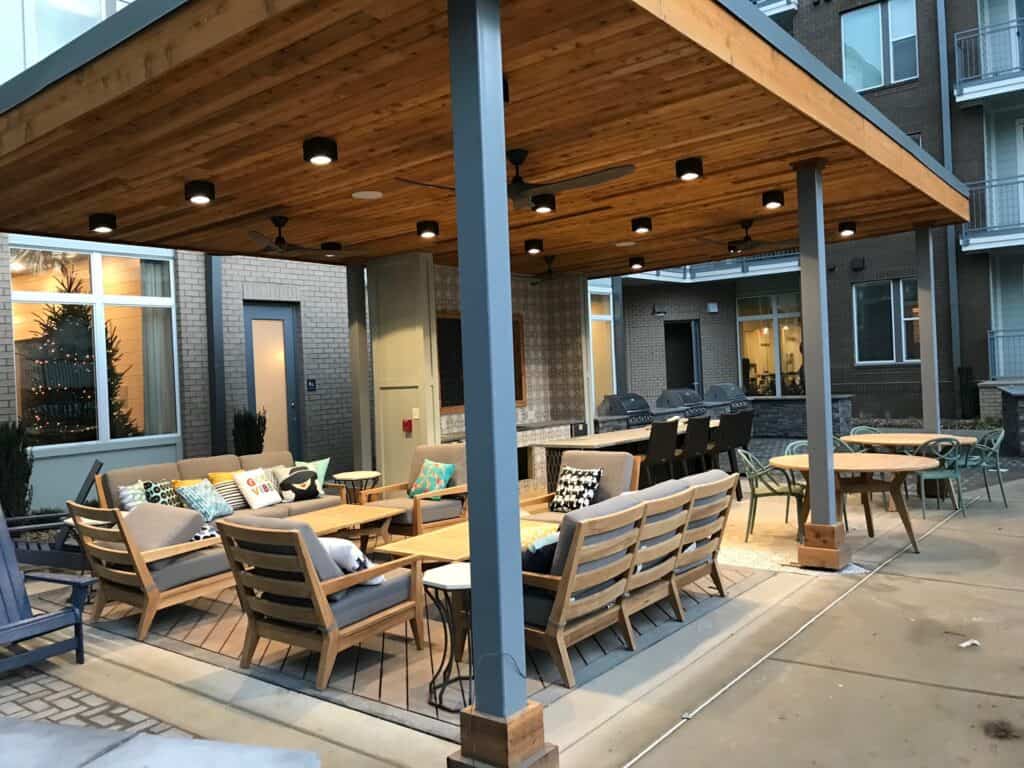 Outdoor living space featuring a wooden pergola, comfortable seating with decorative cushions, and a dining area, showcasing DW Construction's design expertise in creating inviting patios and porches.