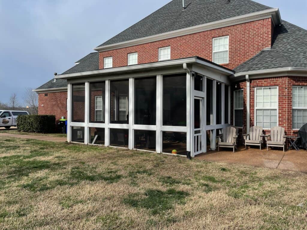Screened-in porch addition to a brick house, featuring outdoor seating and a grassy yard, showcasing DW Construction's outdoor living project expertise in Nashville.