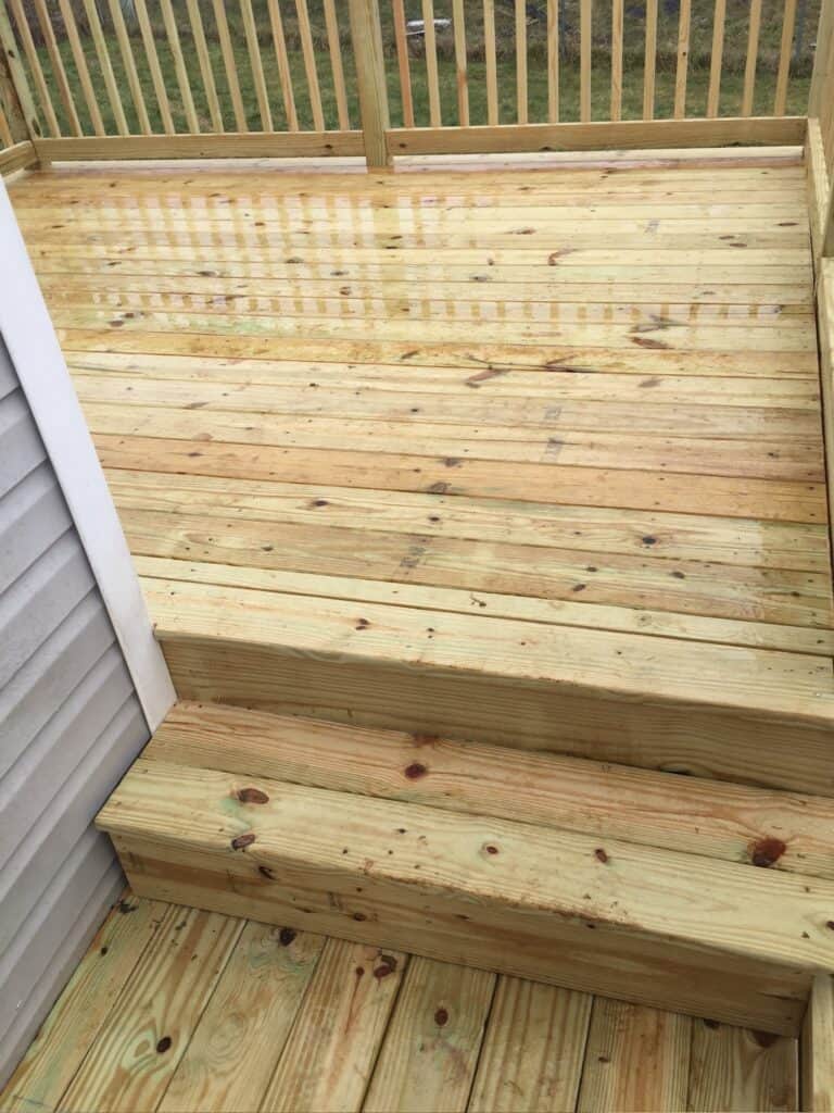 Newly constructed wooden deck with steps, showcasing smooth planks and railing, highlighting outdoor living design by DW Construction in Nashville.