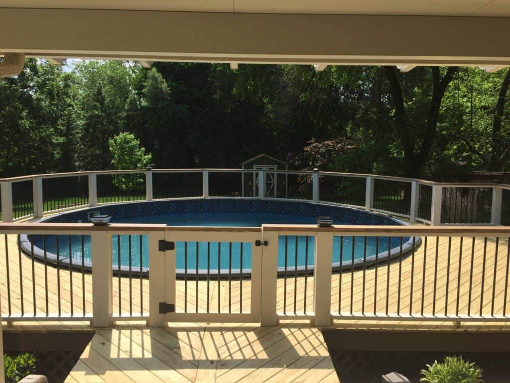 Deck surrounding a circular above-ground pool, with wooden railing and lush greenery in the background, showcasing outdoor living design by DW Construction in Nashville, TN.