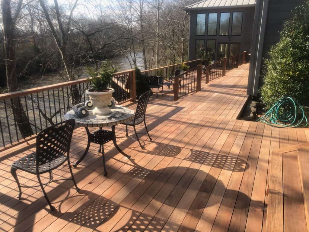 Outdoor wooden deck with a table and chairs, overlooking a river, showcasing a serene outdoor living space designed by DW Construction in Nashville, TN.