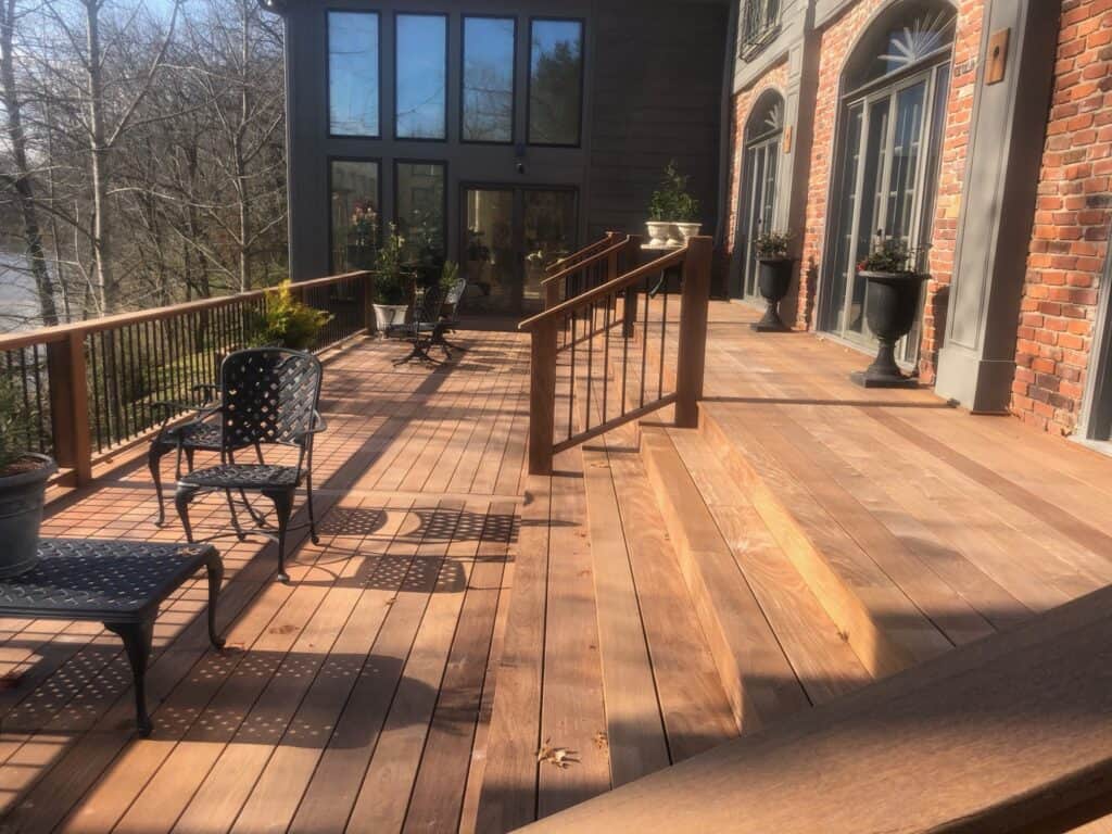 Spacious wooden deck with stylish black chairs, railing, and potted plants, showcasing outdoor living design by DW Construction in Nashville.