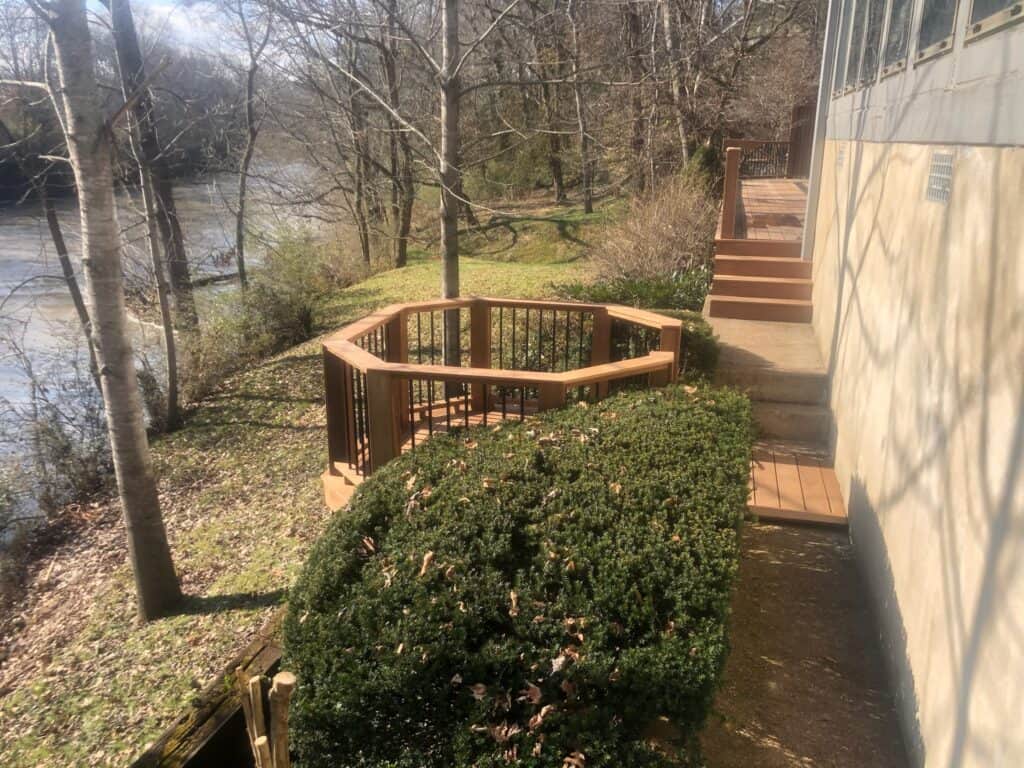 Custom outdoor deck and seating area overlooking a river, surrounded by trees and greenery, showcasing DW Construction's craftsmanship in outdoor living design.