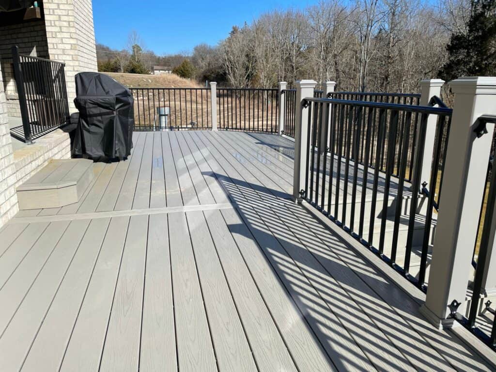 Deck with gray composite flooring, black railing, and a covered grill, showcasing an outdoor living space designed by DW Construction in Nashville.