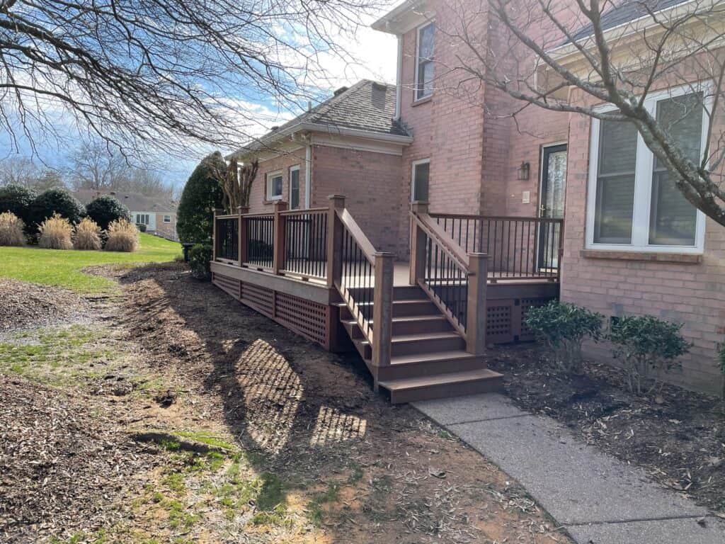 Custom wooden deck with stairs, surrounded by landscaping, showcasing outdoor living space designed by DW Construction in Nashville, TN.