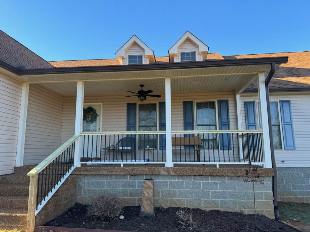 Front porch of a house featuring a ceiling fan, railing, and decorative elements, showcasing outdoor living design by DW Construction in Nashville.