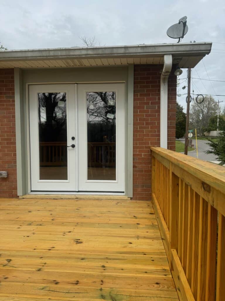 Double doors leading to a wooden deck, showcasing a custom outdoor living space with natural wood railings, ideal for decks and patios in Nashville.