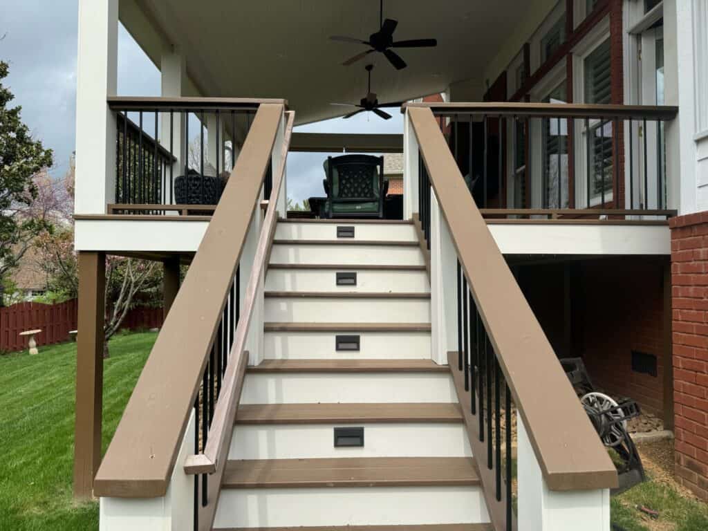 Stairs leading to a covered outdoor living space with black railing and ceiling fan, showcasing a custom deck design by DW Construction in Nashville, TN.