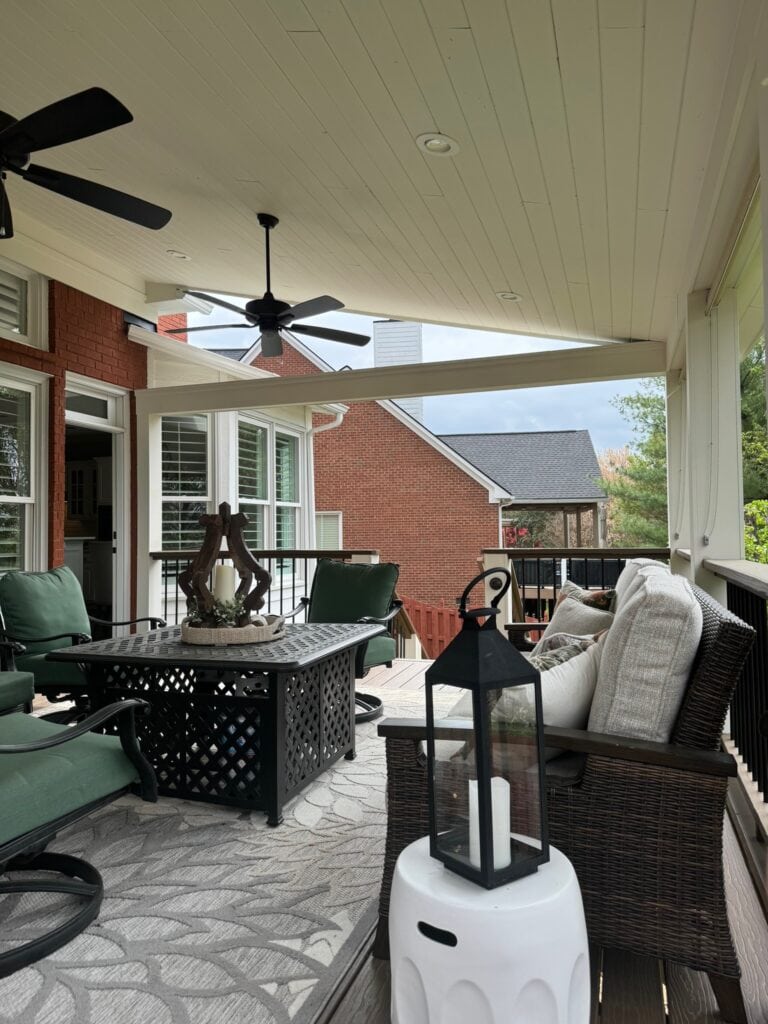 Covered outdoor living space featuring a cozy seating area with green chairs, a decorative table, and stylish lanterns, showcasing DW Construction's custom design for patios and porches in Nashville.