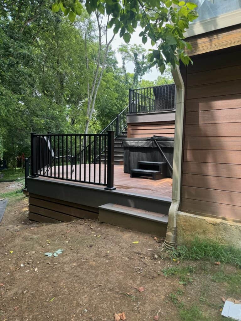 Custom outdoor deck with black railing and steps, surrounded by greenery, showcasing DW Construction's expertise in outdoor living projects in Nashville.