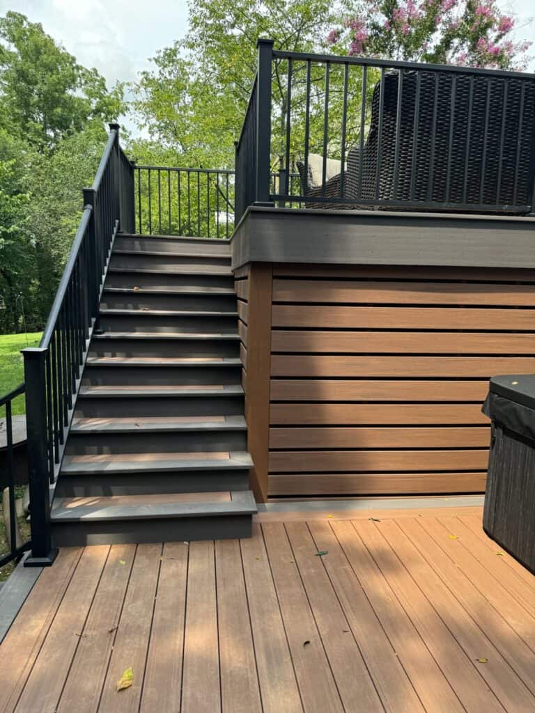 Stairs leading to a custom deck with dark railing and wooden siding, showcasing outdoor living design by DW Construction in Nashville.